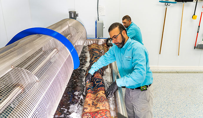 Experienced technician washing an oriental rug in an immersion tub