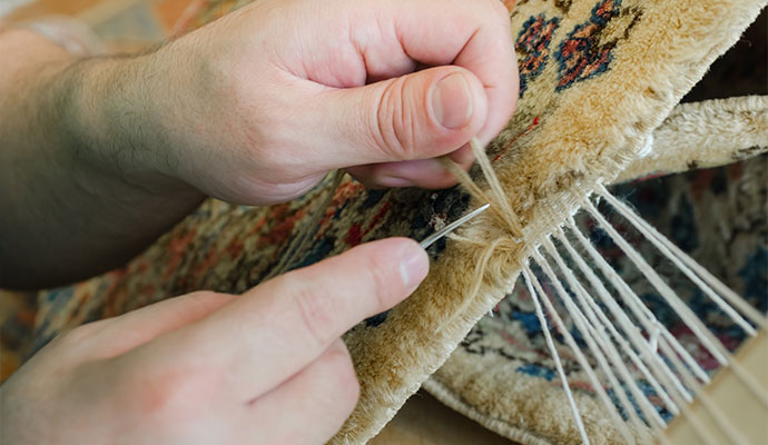 Hand stitching and repairing an oriental rug edge