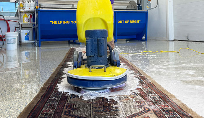 Rotary scrubbing machine cleaning a runner rug for odor removal
