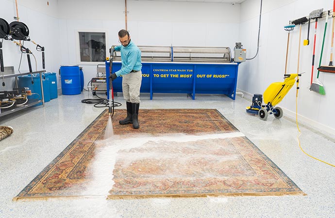 A person deep cleaning a dirty rug using professional equipment
