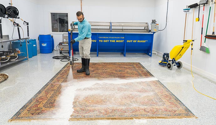 Professional worker using cleaning equipment to deep clean a dirty rug