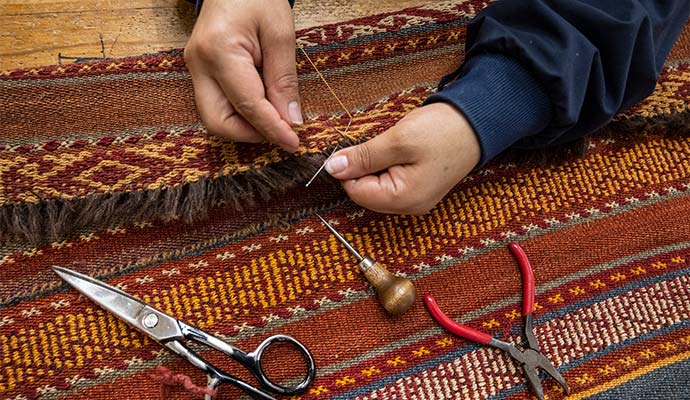 Rug repair specialist stitching and restoring fringe