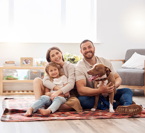 Happy family relaxing with their dog on a clean area rug at home