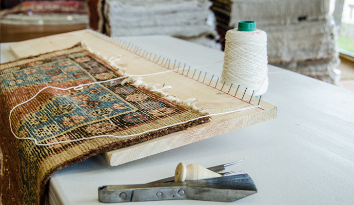 Close-up of a professional rug fringe repair setup with tools and fabric materials