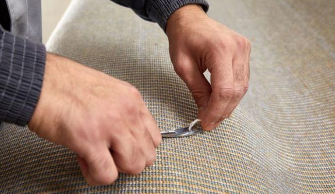 Expert repairing the rug backing using professional tools