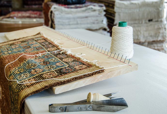 Close-up of a professional rug repair setup with tools and fabric materials