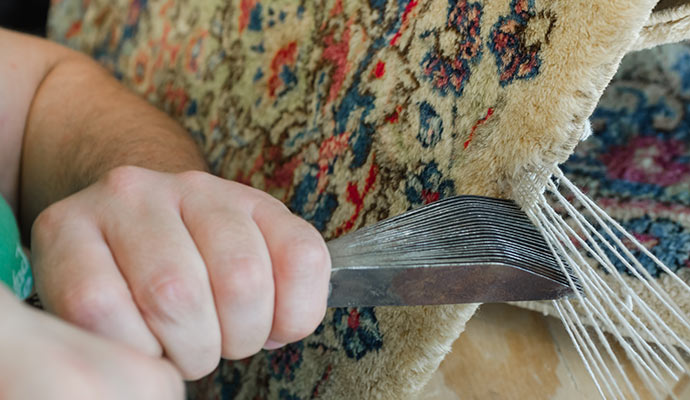 Technician performing detailed rug reweaving and repair work