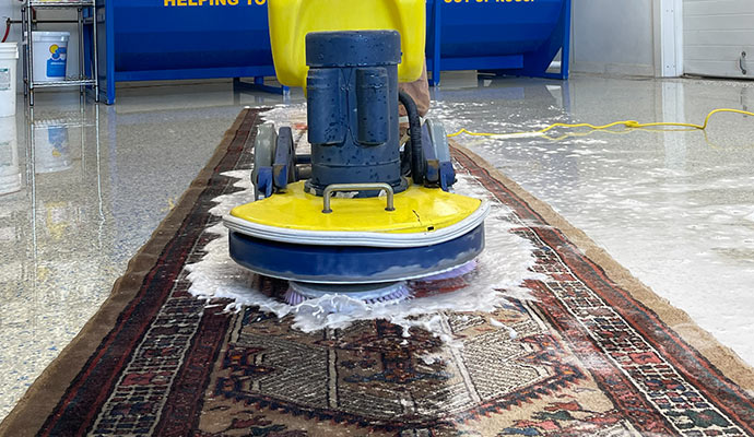 Professional cleaning a rug using machine.