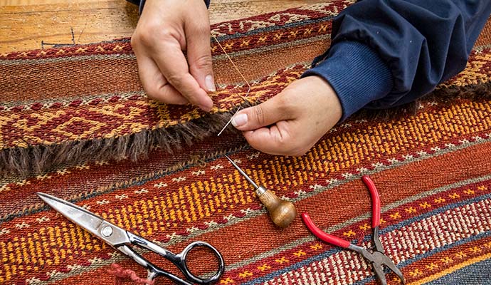 Technician repairing and restoring fringe on a woven rug