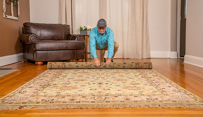 Technician rolling up an oriental rug for pickup service