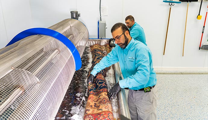 Technician washing an oriental rug inside an immersion wash tub