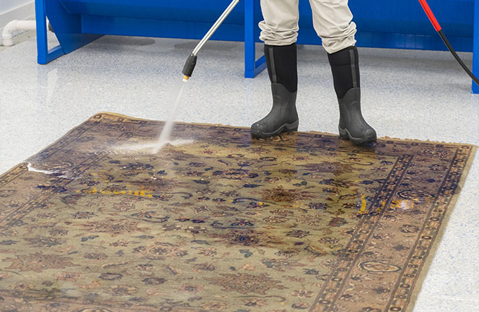 worker rug is removing stains and cleaning the rug with water-wash